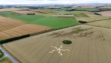 Vista-Aérea-Que-Orbita-La-Formación-De-Círculos-De-Cultivos-De-La-Estrella-De-Salisbury-Y-El-Movimiento-De-Tierras-De-Stone-Henge-En-Un-Vasto-Paisaje-Rural