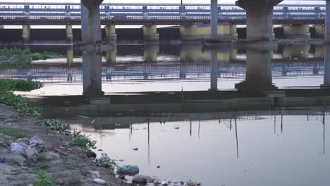 Garbage-at-the-shore-of-Yamuna-riverfront-in-Kalinidi-Kunj-Ghat,-Yamuna-River-port,-New-Delhi