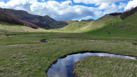 Flight-over-a-winding-mountain-stream-with-clear-water-on-a-sunny-spring-day