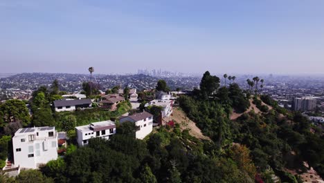 Malerische-Luftaufnahme-Von-Häusern-Am-Hang-Mit-Der-Weitläufigen-Stadtlandschaft-Von-Los-Angeles-Im-Hintergrund-Unter-Einem-Klaren-Blauen-Himmel