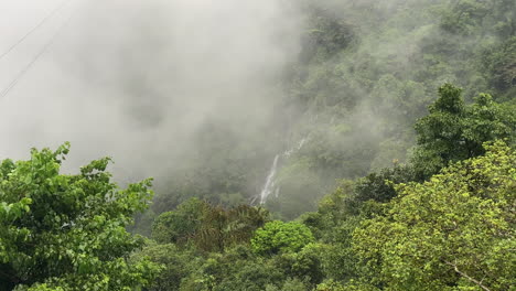 View-of-tropical-landscape-on-foggy-and-windy-day,-waterfall-in-background