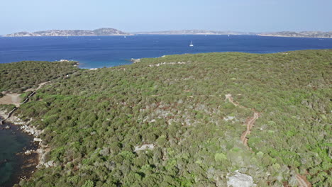 A-lush-green-coastal-landscape-with-the-blue-sea-and-islands-in-the-background,-aerial-view