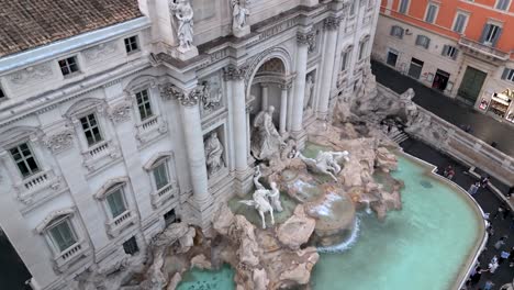 Descending-aerial-down-Trevi-Fountain-facade-in-Rome,-Italy,-seagull-in-view