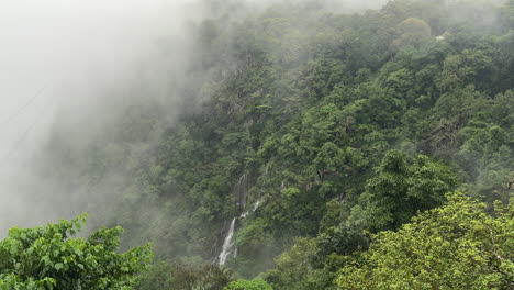 Static-shot-of-tropical-landscape-on-foggy-day,-waterfall-in-background