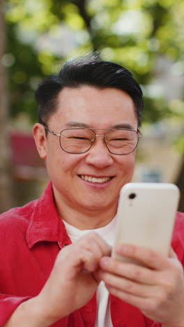 Asian-middle-aged-man-using-smartphone-typing-text-messages-in-social-media-application-online