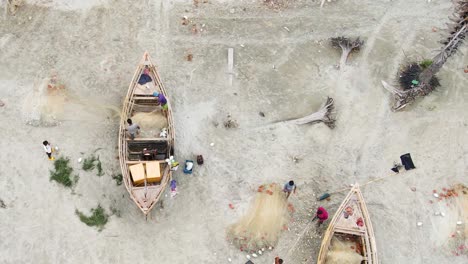 Top-down-aerial-shot-of-fishermen-organizing-fishing-nets-on-a-sandy-beach-in-Bangladesh