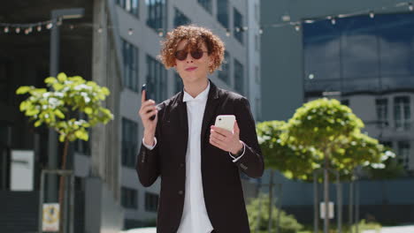 Angry-confused-puzzled-business-man-shouting-talking-on-two-mobile-phones-on-street-outside-office