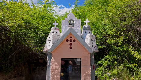 Mini-church-scuplture-in-greece-on-a-sunny-day,-going-forward