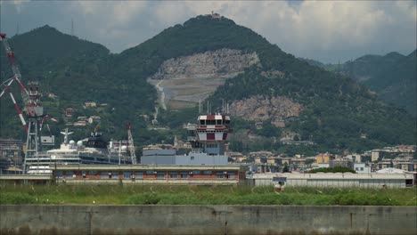 Air-traffic-control-tower-in-the-city-landscape,-tracking-close-up-shot,-tall-mountains-in-the-background,-sunny-day