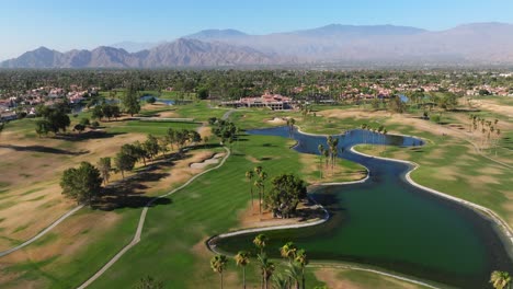 Retroceso-Aéreo-Sobre-Un-Campo-De-Golf-En-El-Centro-De-Palm-Springs,-California,-EE.-UU.,-Comunidad-Con-Una-Gran-Fuente-De-Agua-En-Un-Día-Soleado