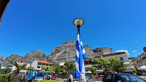 Picturesque-scene-of-Kastraki-against-a-dramatic-backdrop-of-towering-rock-formations-with-Greek-flag-adding-a-patriotic-touch