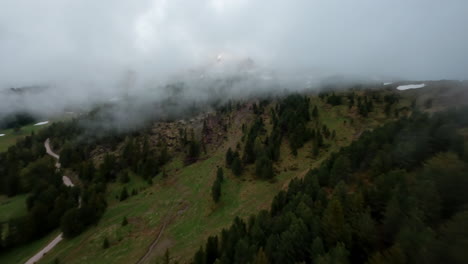 Latemar-mountains-in-trentino-surrounded-by-mist-and-green-landscape,-aerial-view