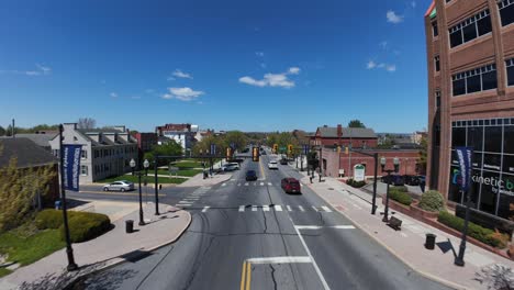 Traffic-on-main-street-of-american-town-with-american-flag