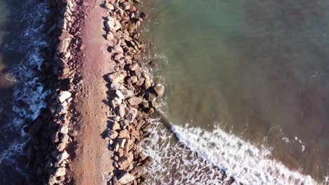 Seaside-Groynes-divider-patch-on-the-beach,-sea-separation,-aerial-top-down