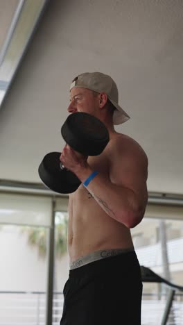 Vertical-low-angle-view-of-male-perform-standing-dumbbell-biceps-curls