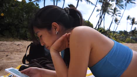 Sideview-of-woman-lying-down-at-the-beach-in-Hawaii-as-cloud-passes-over-sun-then-leaves