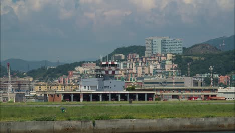 Air-traffic-control-tower-in-the-city-landscape,-tracking-close-up-shot,-tall-buildings-in-the-background,-sunny-day