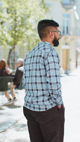 Happy-Indian-man-smiling-turning-looking-at-camera-resting-good-news-feel-satisfied-on-city-street