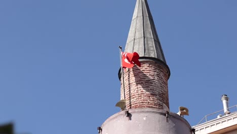 View-of-a-minaret-with-the-Turkish-flag-waving-in-Istanbul,-Turkey