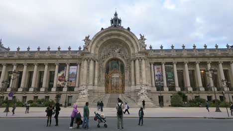 Tourists-walk-and-take-photos-in-front-of-the-Petit-Palais-Art-Museum's-main-entrance-in-Paris,-France