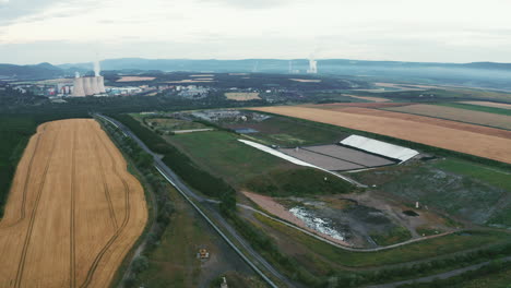 High-quality-footage-of-landfill-with-flyover-geomembrane,-drone-cruising-over-geomembrane,-nature-surrounding-energy-plant-chimneys,-showcasing-environmental-themes