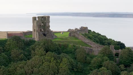 Aerial-drone-view-of-Scarborough-Castle-in-Scarborough,-North-Yorkshire-taken-early-morning-on-an-overcast-day-in-summer