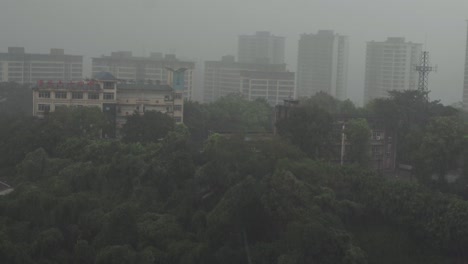 A-foggy-urban-scene-with-multiple-high-rise-buildings-in-the-background,-a-school-building-with-red-signage-in-the-foreground,-and-lush-green-trees-covering-the-lower-part-of-the-image