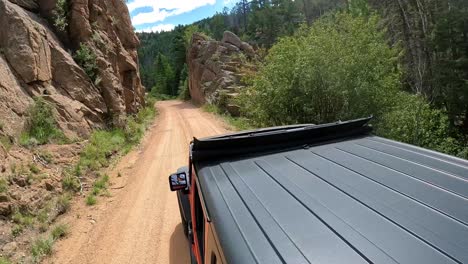 POV---View-of-vehicle-rooftop-driving-thru-cut-away-in-granite-embankment-on-Phantom-Canyon-Road-in-Colorado