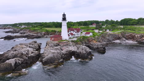 Idyllic-New-England-scene,-aerial-zoom-out-revealing-Portland-Head-Light-and-Maine-coastline