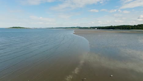 Slow-motion-aerial-of-flocks-of-birds-flying-along-scenic-beach-with-water-reflection-on-low-tide,-Scottish-coast-seabirds-in-slowmo