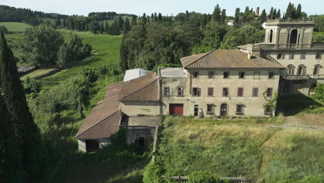 Abandoned-villa-in-rural-Italy-surrounded-by-lush-greenery,-shot-from-an-aerial-view