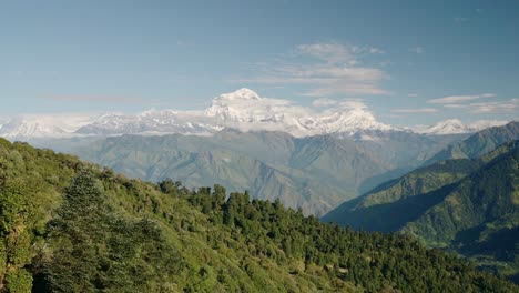 Paisaje-Exuberante-De-Las-Montañas-Verdes-Del-Himalaya-En-Nepal,-Paisaje-De-Montaña-Exuberante-Con-árboles-En-Las-Estribaciones-Del-Himalaya-Con-Montañas-Cubiertas-De-Nieve-Detrás-En-Un-Día-Soleado-Con-Cielo-Azul