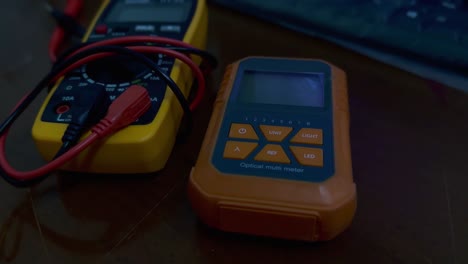 Optical-Power-Meter-Cable-Tester-and-Multimeter-on-the-wooden-table