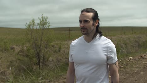 Man-walking-on-dirt-road-by-expansive-fields