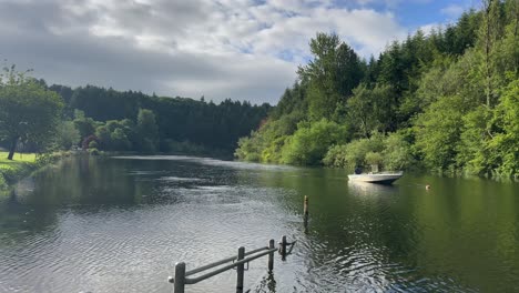 Motorboat-moored-in-slow-moving-peaceful-river-in-green-countryside