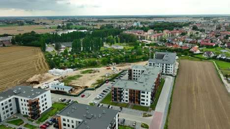 Aerial-shot-of-a-new-residential-district-next-to-agricultural-fields,-illustrating-the-expansion-of-urban-areas-into-rural-landscapes