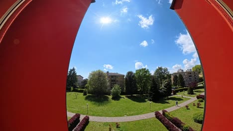 Timelapse-video-of-a-sunny-day,-featuring-a-vibrant-green-park-surrounded-by-residential-buildings