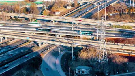 Vogelperspektive-Bei-Nacht-Mit-Hellem-Stadtblick-Auf-Mehrstöckige-Kreuzungsstraßen-Mit-Fahrenden-Autos,-Verkehr-Auf-Einer-Modernen-Autobahn-Mit-Überführungsbrücke-Auf-Dem-Land-In-Der-Nähe-Von-Bootsströmen-Im-Fluss