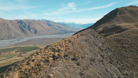 New-Zealand-Mountain-Peak-Drone-Fly-Over-As-Hiker-Walks-Downhill