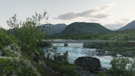 Varios-Vehículos-Cruzando-Un-Hermoso-Puente-En-Un-Paisaje-Espectacular-En-Jotunheimen,-Noruega