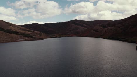 Aerial-drone-shot-flying-over-the-lake-and-rising-to-show-a-mountain-range-in-Salt-Lake-City-with-fall-colored-leaves-at-60fps