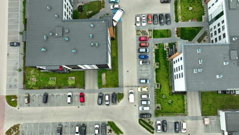 Drone-view-of-an-urban-residential-area-with-rows-of-parked-cars-along-the-streets-and-between-apartment-buildings,-highlighting-the-density-of-urban-housing