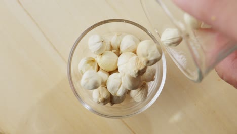 Cardamom-seeds-being-poured-into-a-glass-bowl-in-slow-motion,-top-view