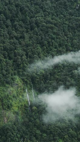 Vertikale-Luftaufnahme-Eines-Wasserfalls-In-Wolken,-Vertikales-Video-Für-Social-Media-Instagram-Reels-Und-Tiktok-Von-Wasserfällen-Mit-Himalaya-Bergen-Und-Grünem-Wald-Aus-Bäumen-In-üppiger-Grüner-Waldlandschaft