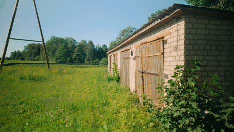 Abandoned-barn-with-rustic-wooden-doors-stands-in-a-verdant-summer-landscape