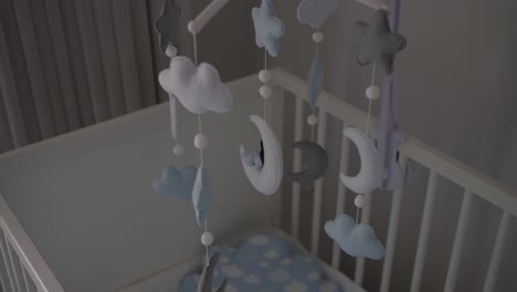 Soft-pastel-mobile-with-clouds,-stars,-and-moons-hanging-above-a-crib,-creating-a-calming-and-dreamy-atmosphere-in-a-nursery