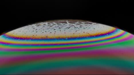 Close-up-of-a-vibrant-soap-bubble-surface-with-swirling-rainbow-colors-against-a-black-background