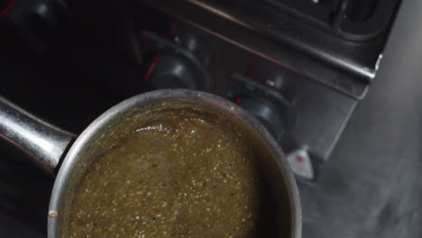 Beautiful-slow-motion-shot-as-a-chef-pours-green-salsa-into-a-metal-pot-with-a-ladle-inside-a-kitchen-at-a-Mexican-restaurant