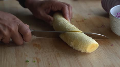 Cortar-Plátano-Amarillo-En-Trozos-Pequeños-E-Ingredientes-Especiales-Para-Cocinar-Una-Comida-Dos-Latas-De-Frijoles-Arroz-Plátano-Aguacate-Cebolla-Roja-Y-Cilantro