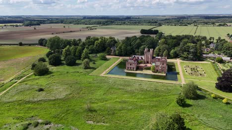 Oxburgh-Estate,-Herrenhaus-Aus-Dem-15.-Jahrhundert-Mit-Wassergraben,-Norfolk,-Großbritannien,-Hochwinklige-Drohne,-Luftaufnahme